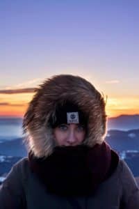 Foto de uma mulher usando um casaco pesado de frio possivelmente em algum lugar com neve.