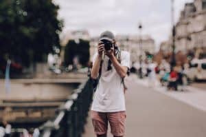 Um homem segurando uma máquina fotográfica como se fosse tirar uma foto com o resultado final da edição