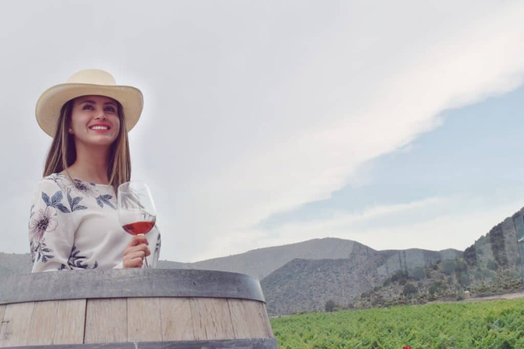 mujer con sombrero rojo y abanico rojo en terraza con montañas detrás 