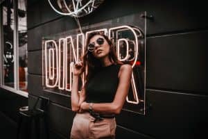 Foto de uma mulher posando em frente a uma placa escrito "Diner" com edição final. 