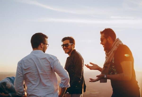 Foto de três amigos juntos e rindo durante um pôr-do-sol 