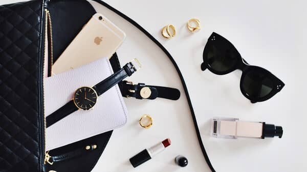 flatlay de colores neutros, con mucho negro, lentes, maquillaje y joyería