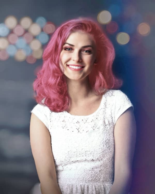 retrato de mujer sonriendo, con maquillaje llamativo y cabello rosa