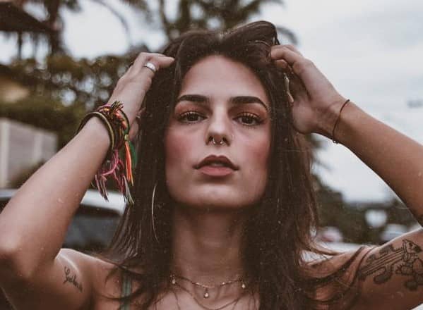 mujer en la playa, con tatuajes, joyería y maquillaje