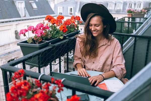 mujer rubia con sombrero trabajando en un balcón en Paris