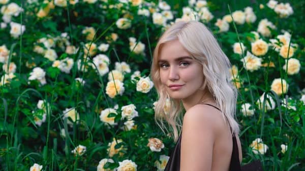 Chica rubia con flores en el fondo