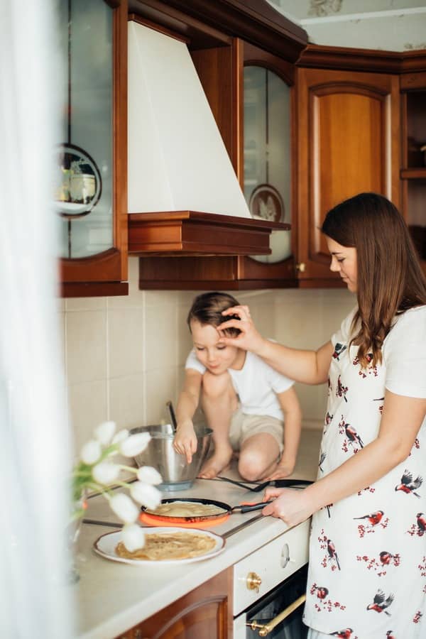 Mamá en la cocina cocinando junto con su hijo varón de 5 años. 