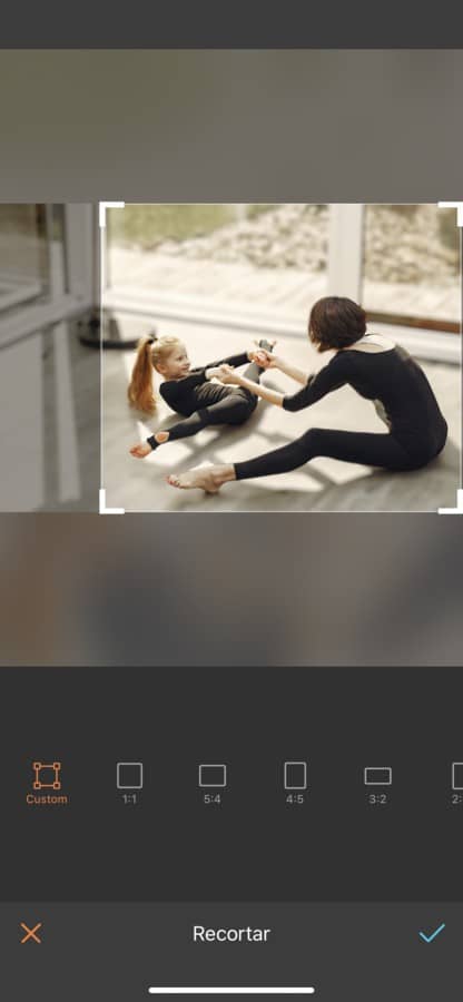 Foto de mamá practicando ballet o gimnasia con su hija. Ambas están vestidas con un payasito negro y están haciendo estiramientos.