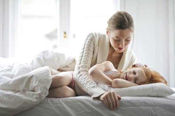 Mamá viendo cómo duerme su hija sobre la cama 