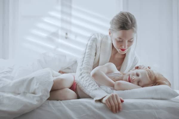 Mamá viendo cómo duerme su hija sobre la cama 