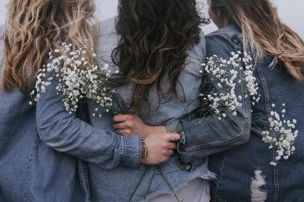 three women embracing holding baby's breath