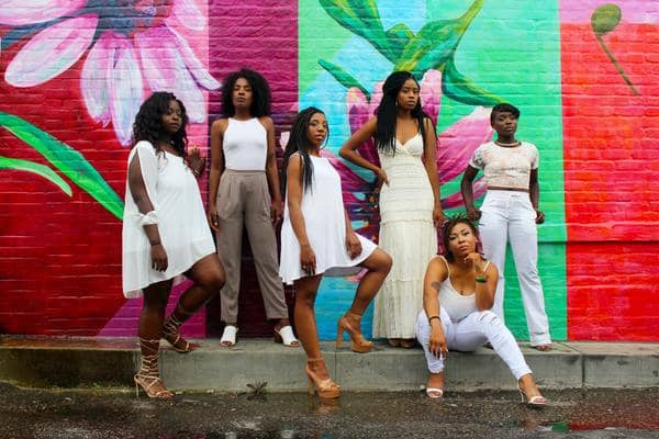 women standing and sitting in front of a colorful mural