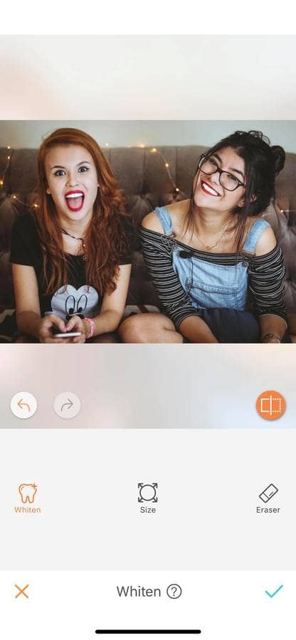 two women sitting on a gray couch, smiling