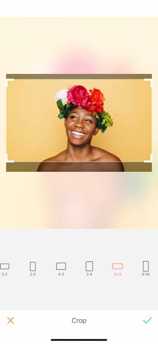 Picture of bald black woman with a crown of flowers being edited by AirBrush with the Crop Tool