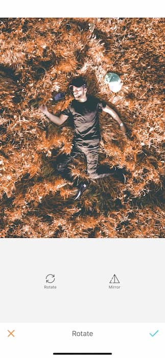 Picture of a guy lay down in a dry grass being edited by AirBrush with the Rotate Tool