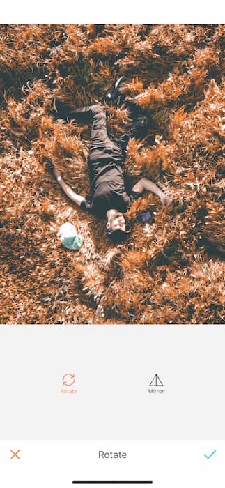 Picture of a guy lay down in a dry grass being edited by AirBrush with the Rotate Tool