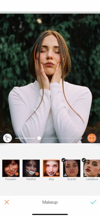 woman wearing a white top holds her face in her hands