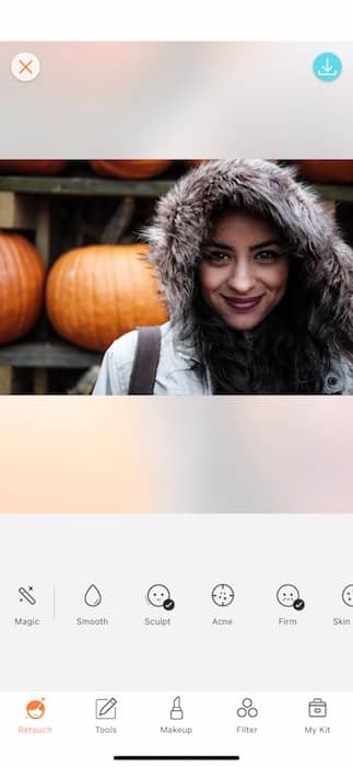 smiling woman wearing hooded jacket stands in front of pumpkins