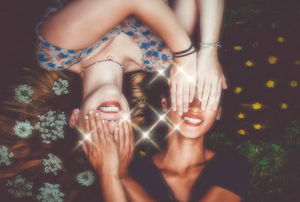 sparkly photo of women covering each other's eyes and smiling