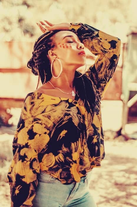 woman with long braids wearing a multi-colored shirt 