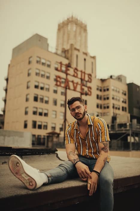 man sitting on rooftop in front of city skyline