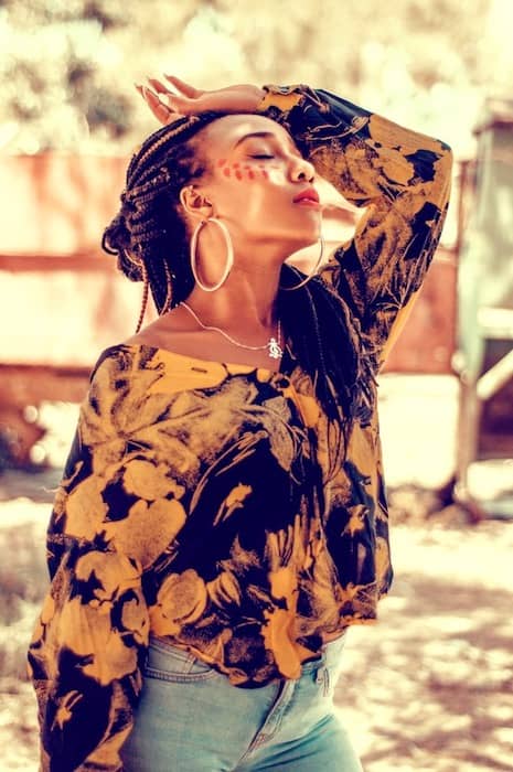 woman with long braids wearing a multi-colored shirt 