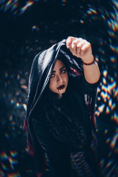 Picture of a woman holding a scarf up her head with vampire Makeup