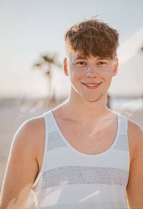 young man in white and grey tank top at the beach