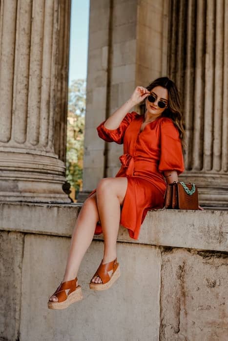 woman wearing orange dress posing in front of pillars