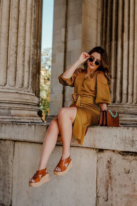 woman wearing gold dress posing in front of pillars