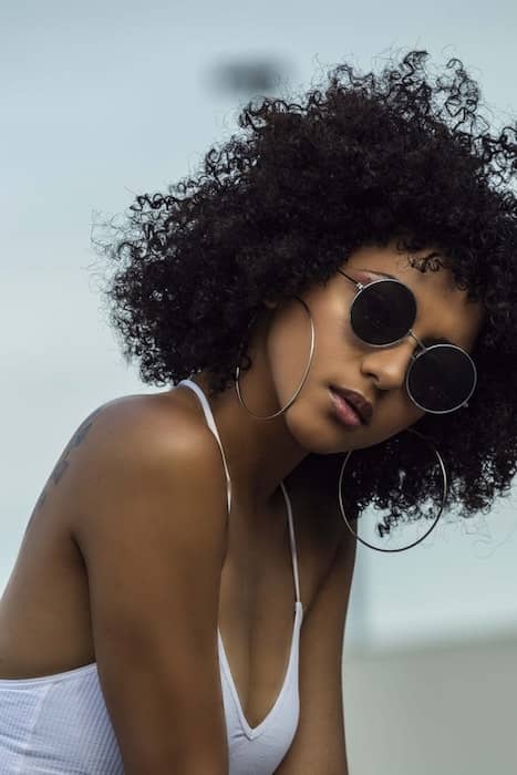 black woman wearing sunglasses and a white tank top