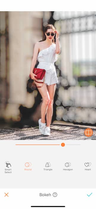 woman in a white romper holding a red purse in front of a blurred background