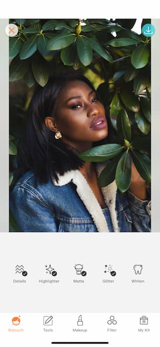 black woman in denim jacket surrounded by green leaves