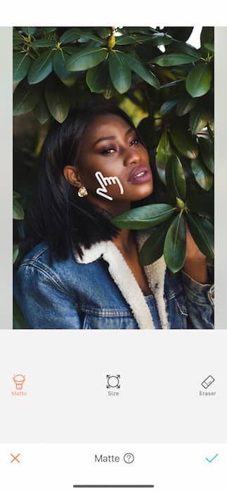 black woman in denim jacket surrounded by green leaves