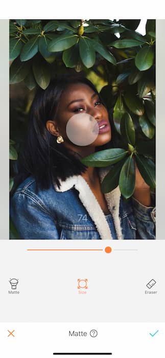 black woman in denim jacket surrounded by green leaves