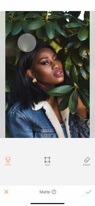 black woman in denim jacket surrounded by green leaves