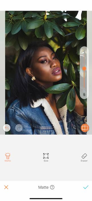 black woman in denim jacket surrounded by green leaves