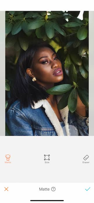 black woman in denim jacket surrounded by green leaves