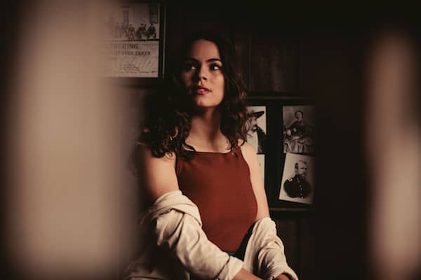 dark haired woman in a red tank top and sweater