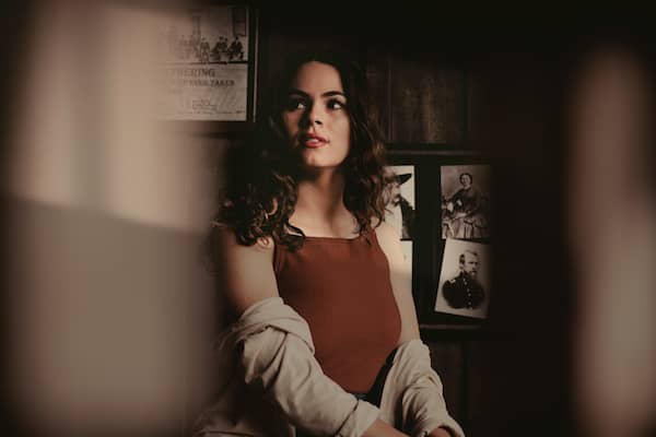 dark haired woman in a red tank top and sweater