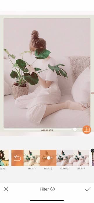 woman sitting on a white couch holding a plant