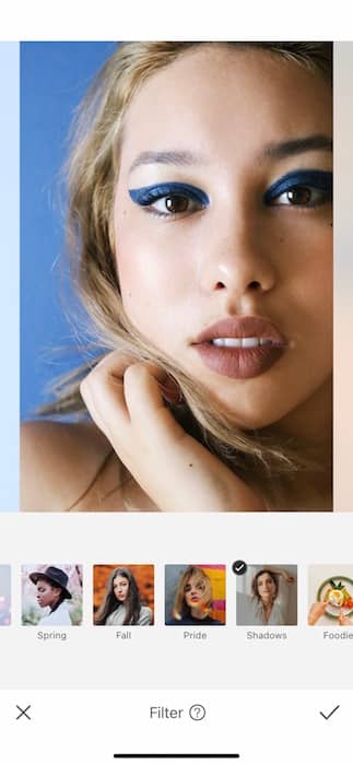 closeup of woman with blonde hair and blue eyeliner in front black background