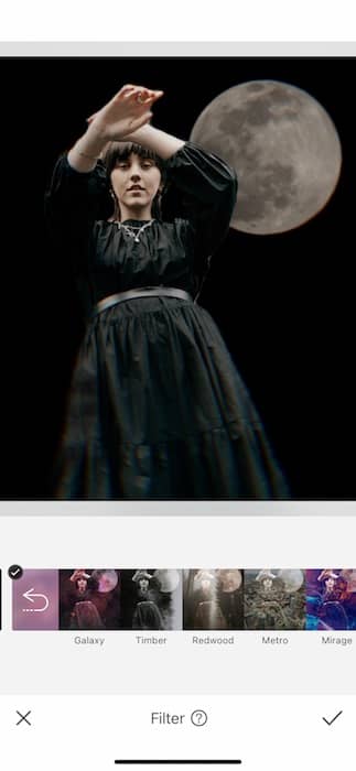 woman wearing a black dress standing in front of the moon