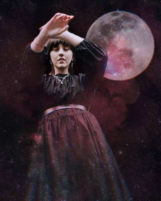 woman wearing a black dress standing in front of the moon