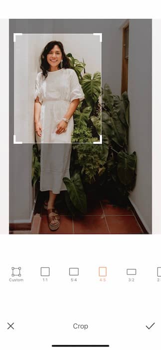  woman in a white dress standing in front of a green plant