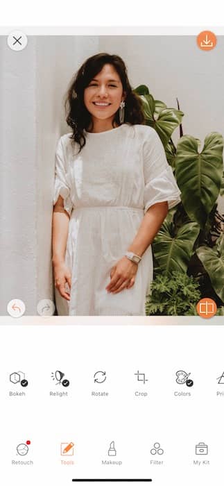  woman in a white dress standing in front of a green plant