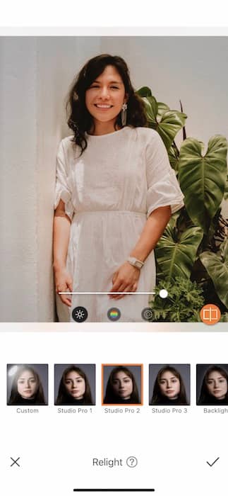  woman in a white dress standing in front of a green plant