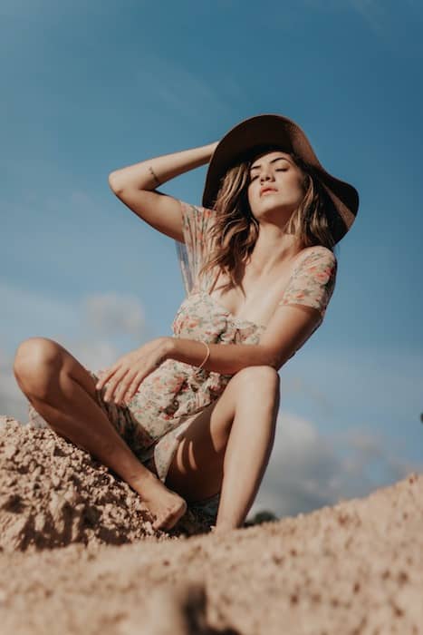 woman wearing a hat sitting in sand