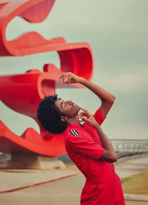 black man in red jumpsuit in front of curvy red sculpture