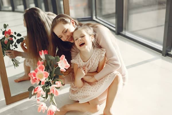 mother hugging toddler daughter and laughing